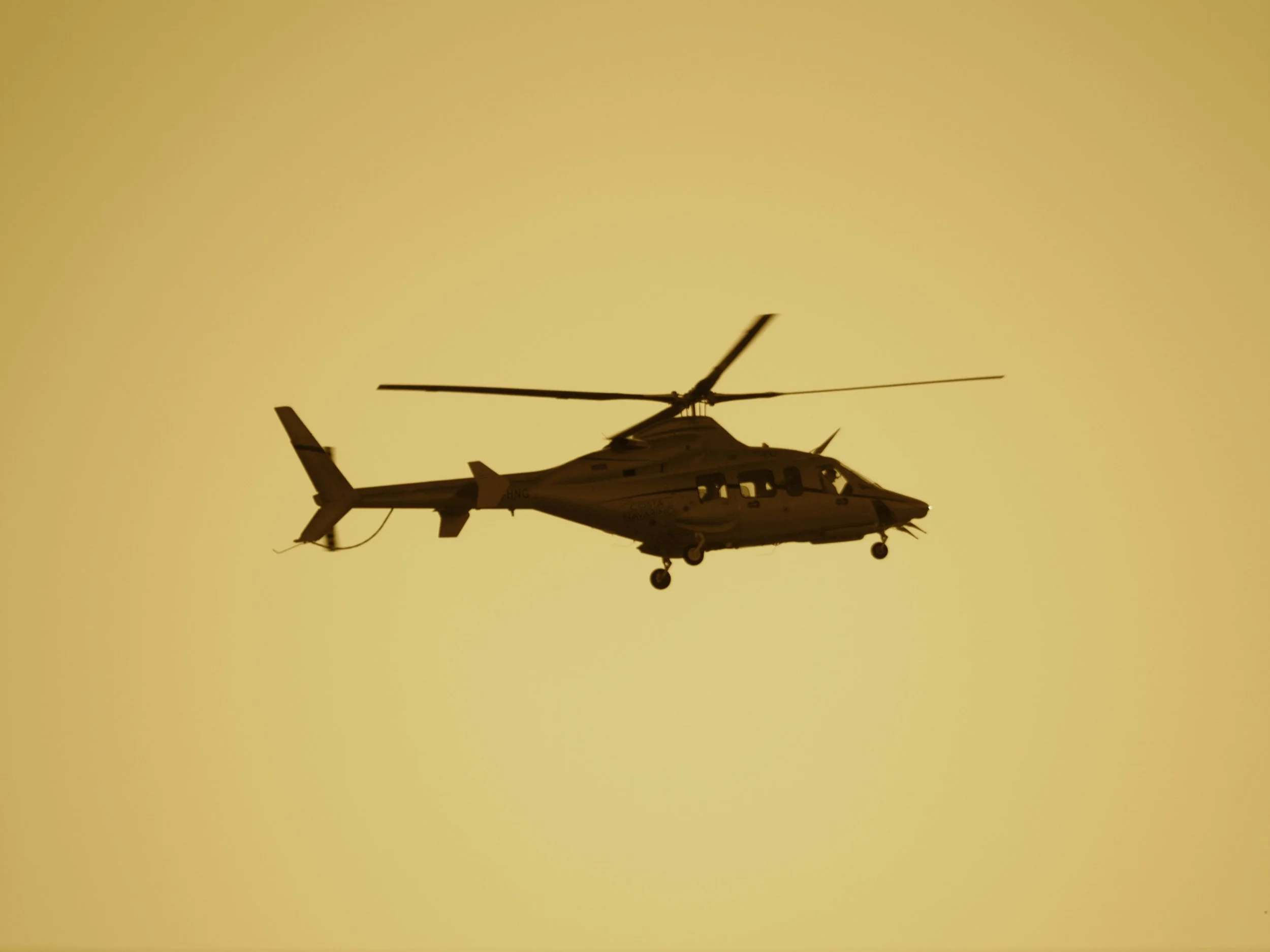 A helicopter crossing a gold evening sky